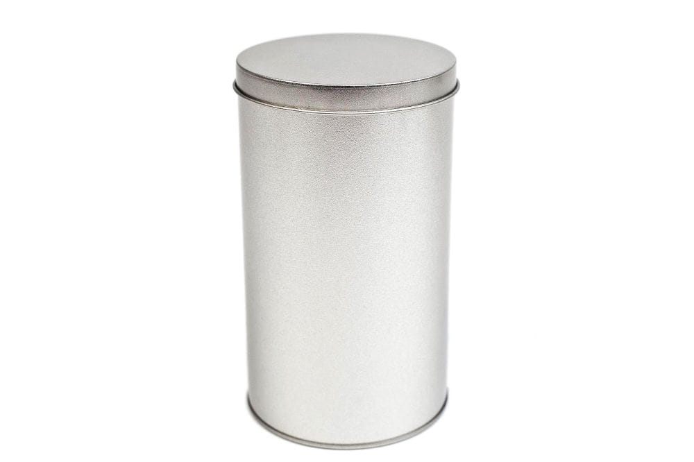 Geschlossene runde Blechdose aus silberfarbenem Metall mit aufgesetztem Stülpdeckel, neutraler Hintergrund.
