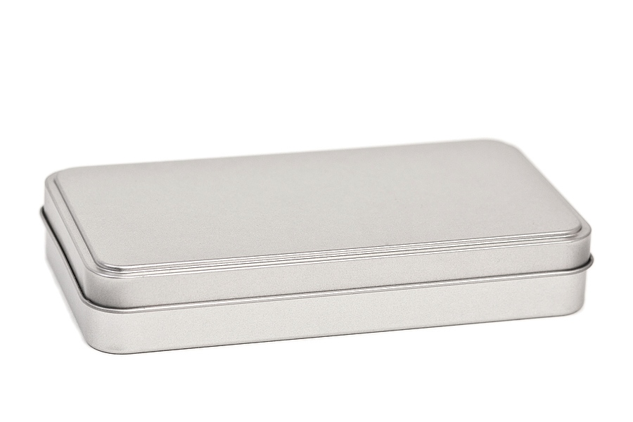 Geschlossene, rechteckige Metallverpackung aus silberfarbenem Blech mit fest schließendem Klappdeckel und unsichtbaren Scharnieren, fotografiert vor neutralem Hintergrund.